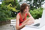 Smiling woman using laptop in backyard