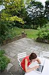 Woman reading and using laptop outdoors