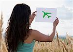 Woman holding picture of airplane in sky