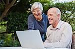 Older couple using laptop outdoors