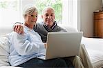 Sourire vieux couple utilisant un ordinateur portable