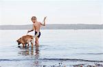 Boy wading with dog on beach