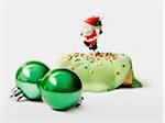 Christmas pistachio individual log cake with a Santa Claus figurine and green Christmas tree balls