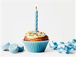 Cupcake with one birthday candle,blue candies and ribbon