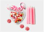 Transparent heart filled with multicolored sugar balls and pink birthday candles