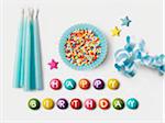 Joyeux anniversaire écrit sur Smarties et une tasse de papier bleu remplie de billes de sucre pour la décoration de gâteaux, de ruban et de bougies d'anniversaire bleu