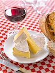 Portions of Camembert, bread and a glass of red wine