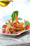 Pouring a drop of olive oil onto the pear and shrimp salad