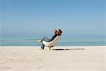 Mid homme relaxant en fauteuil sur la plage