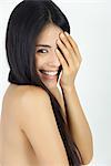 Woman covering one eye, smiling over shoulder at camera