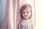 Little girl in front of window, smiling, portrait