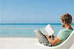 Junger Mann Buch am Strand lesen