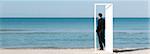 Homme debout sur la plage en regardant l'océan, à travers la porte ouverte