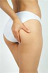 Woman pinching body fat on buttocks, cropped