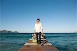 Young man pulling luggage and walking on pier