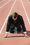 Businessman crouching at starting line on running track