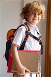 Boy prepared for school, carrying backpack and notebooks