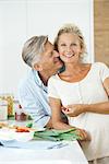 Mature couple together in kitchen, man nuzzling woman, portrait