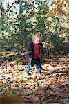 Fille de bambin se promener dans les feuilles d'automne