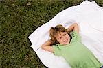 Happy Boy liegend auf einer Decke im Gras, München, Bayern, Deutschland