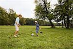 Father and son playing soccer in park, Munich, Bavaria, Germany