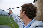 Young man fastening a carabineer to a rope in a high wire park, close-up, selective focus