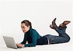 Young woman lying on floor with laptop