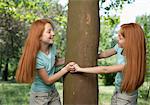 Red haired female twins surrounding a tree