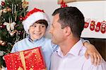 Father and son with present next to Christmas tree