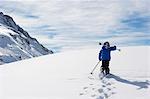 Child carrying skis up snowy mountain