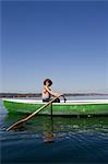 Woman rowing boat in still lake