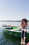 Woman dangling feet from boat in lake