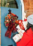 Woman with wrapped gifts at front door