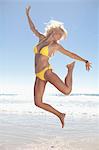 Woman jumping for joy on beach