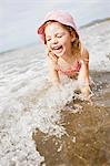 Jeune fille souriante, jouant dans les vagues sur la plage