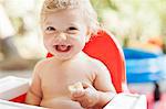 Laughing toddler eating in high chair