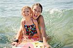 Mother and daughter boarding in ocean