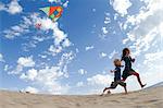 Mother and son flying kite on beach