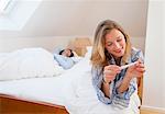 Woman reading pregnancy test on bed