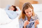 Woman reading pregnancy test on bed