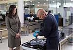 Security Guard Examining Contents of Suitcase in Airport