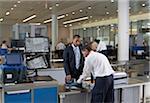 Security Guard Checking Businessman's Luggage in Airport