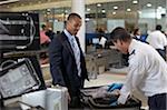 Garde de sécurité vérifiant valise les hommes d'affaires à l'aéroport