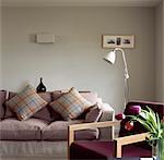 Cushions on sofa and cut tulips with armchair, UK living room.