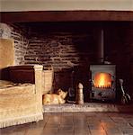 Upholstered sofa in front of woodburning stove in inglenook fireplace