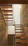 Contemporary wooden staircase in front of tall window