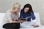 Two girl friends reading a magazine