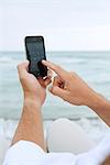 Utilisation du smartphone à la plage, recadrée de l'homme