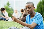 Young man with cell phone, people in background, portrait