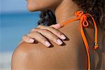 Femme touchant l'épaule nue à la plage, recadrée